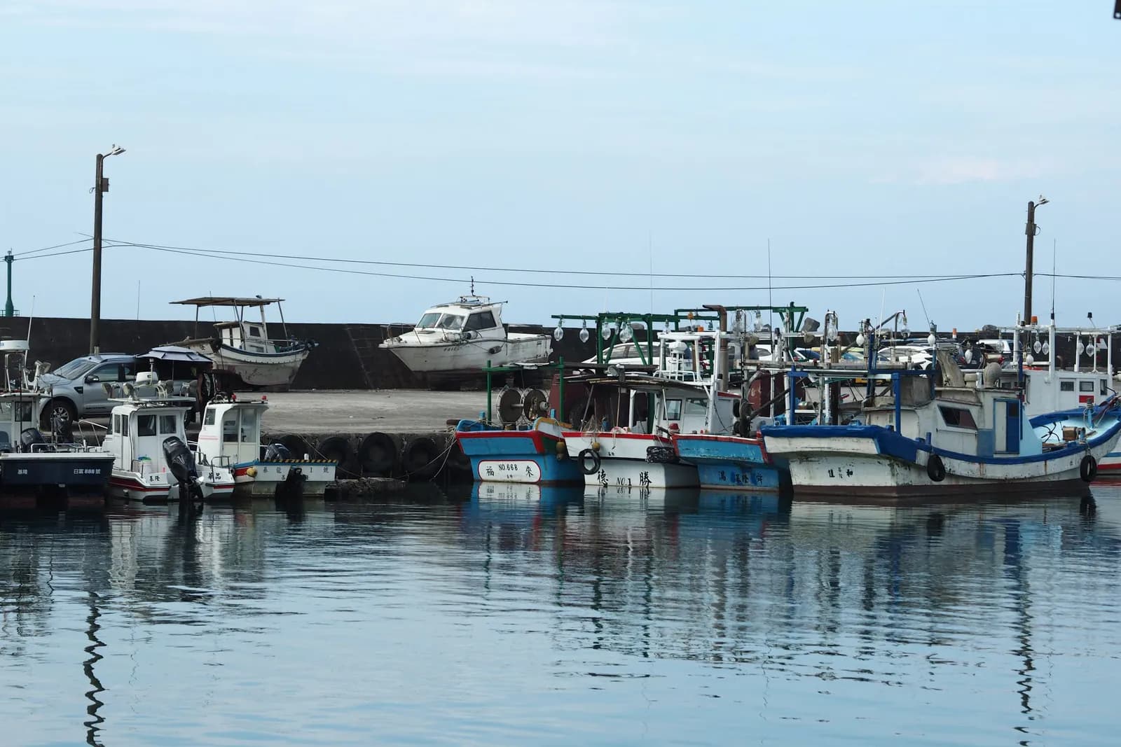 Fishing boats tied up along the dock on a flat, bright morning.